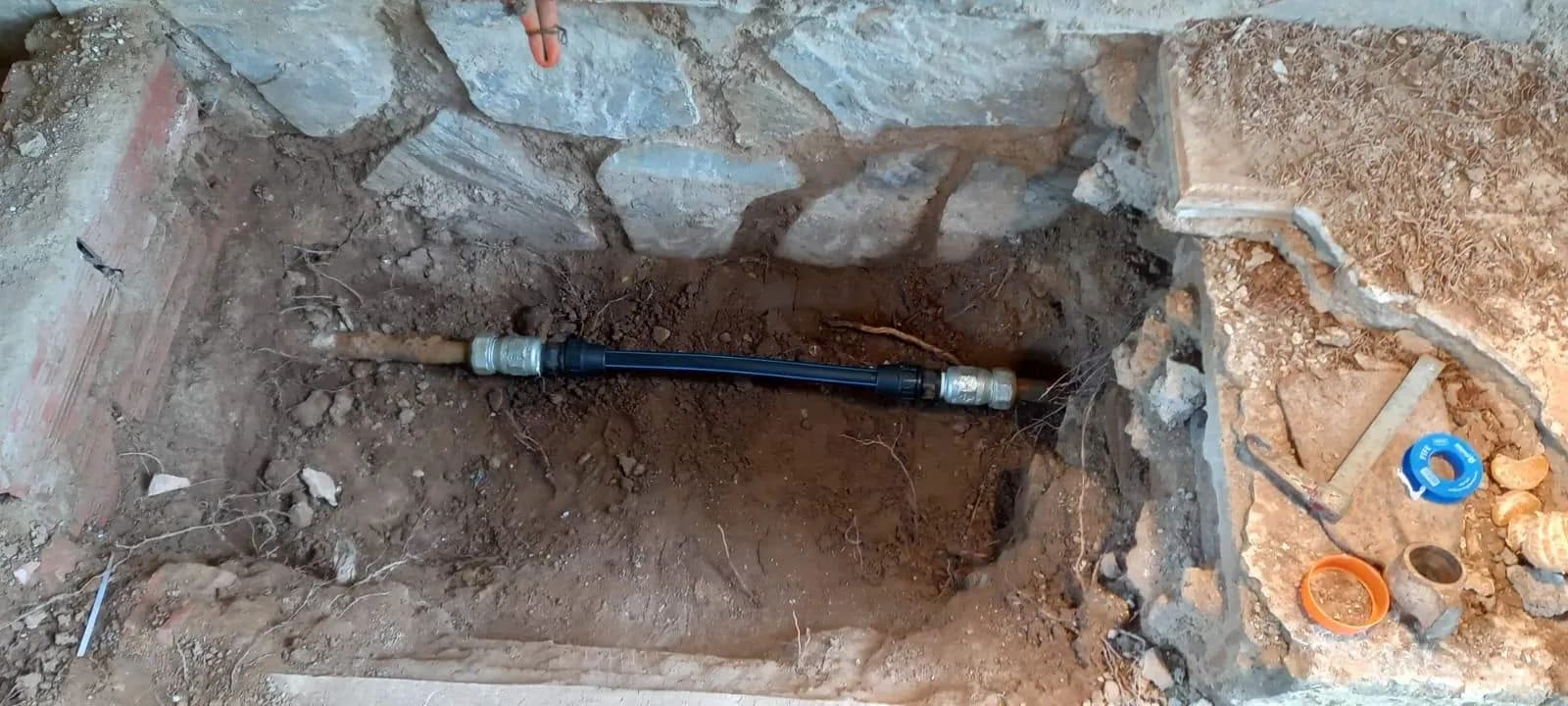 Cata abierta sobre una tubería enterrada con la fuga localizada al descubierto